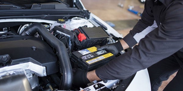 A mechanic installing a buick battery into the vehicle
