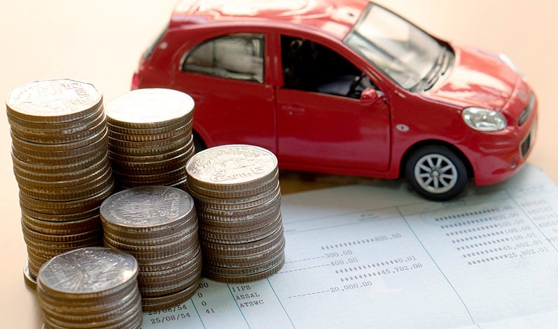 A red toy car and coins on papers